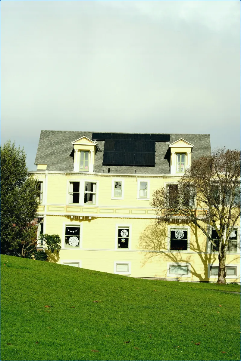 Yellow house with solar panels and green lawn