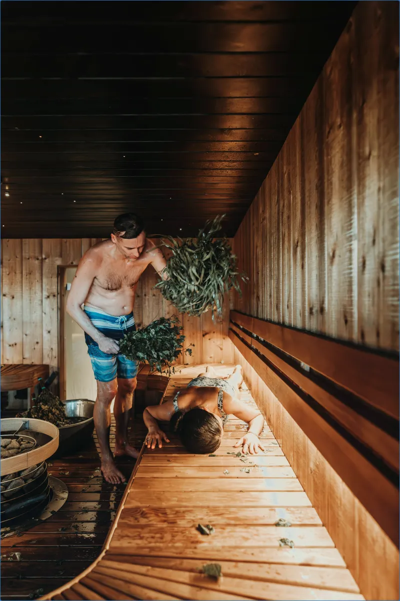 Man giving a sauna treatment with leaves
