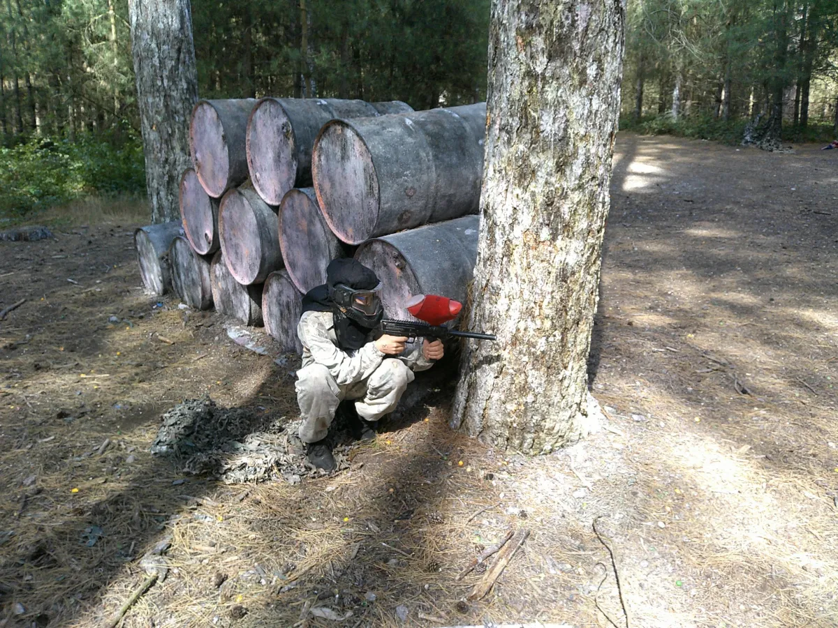 Person playing paintball in a forest setting.